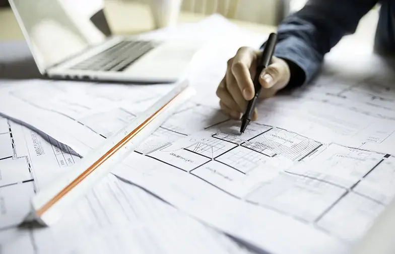 Main annotant un plan technique pour le diagnostic d’une structure bois