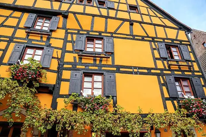 Façade jaune d’une maison alsacienne à colombages