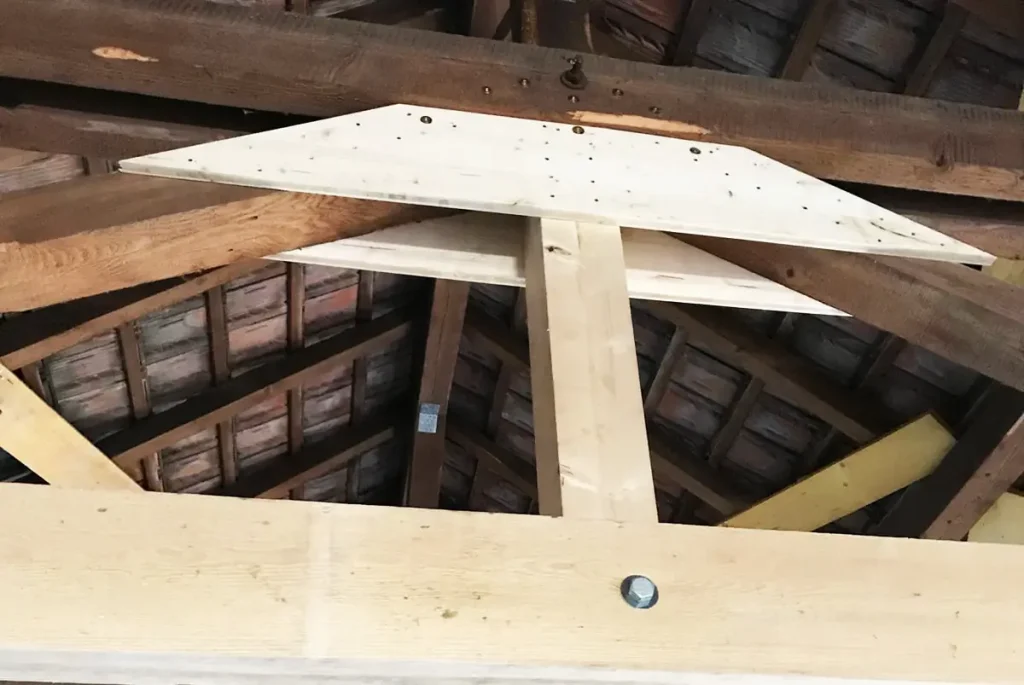 Renfort en bois sous une charpente ancienne